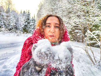 Portrait of smiling young woman standing on snow covered field