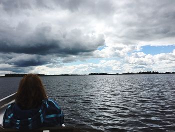 Rear view of woman in boat at sea against sky