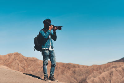 Man photographing on desert against sky