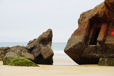 Rock formations on beach against clear sky