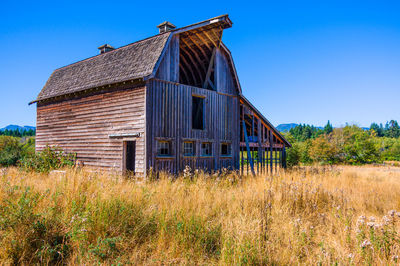 Abandoned built structure on field against clear blue sky