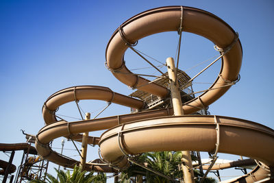 Low angle view of the slide at a water park against clear blue sky 