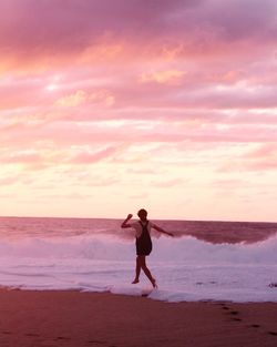 Full length of man standing on beach against sky during sunset