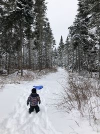 Rear view of girl riding on snow covered land