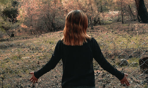 Rear view of woman standing in forest