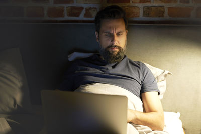 Portrait of young man sitting on sofa at home