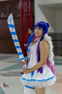 Beautiful young woman holding umbrella standing in corridor