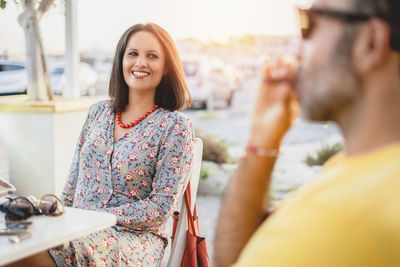 Smiling woman looking at friend while sitting in city