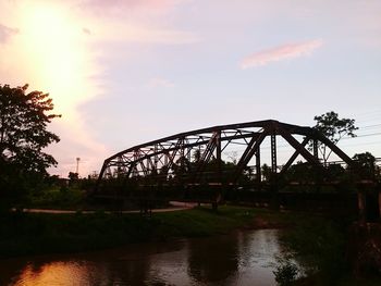 Bridge over river against sky at sunset