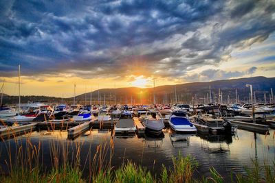 Boats moored at harbor against sky during sunset