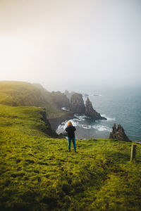 Man standing on shore by sea against sky