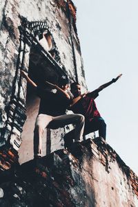 Low angle view of woman sitting on rock against sky