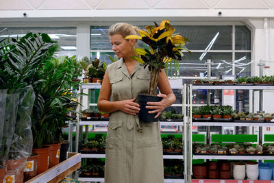 Woman at shopping, young lady choosing home plants in store