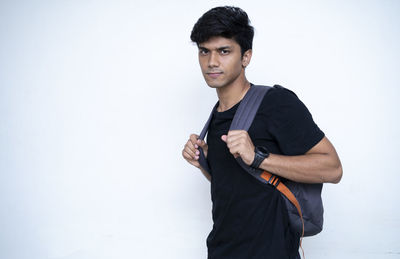 Young man looking away while standing against white background