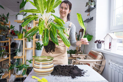 Portrait of woman holding potted plant