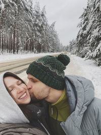 Portrait of young man kissing woman in winter
