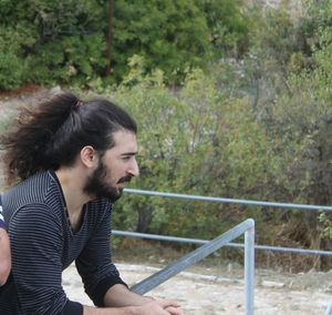 Side view of man looking away against trees