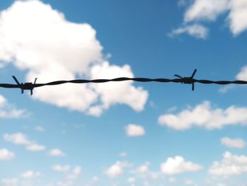 Low angle view of silhouette barbed wire against sky