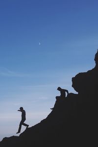 Silhouette men hiking on mountain against sky at dusk