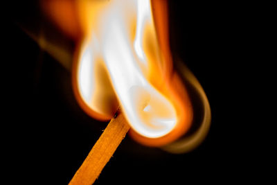 Close-up of lit candle against black background