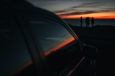 Close-up of silhouette man on car against sky