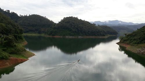 Scenic view of lake by trees against sky