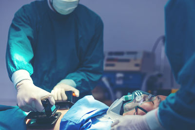 While performing medical surgery inside the operating room, a doctor and nurse use a defibrillator.