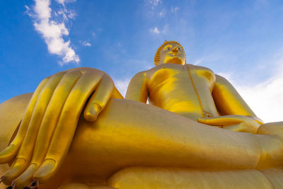 Low angle view of yellow statue against sky