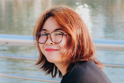 Portrait of smiling young woman against lake