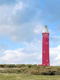 Lighthouse on field against sky