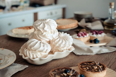 White airy meringue cake on the festive table, in the kitchen.