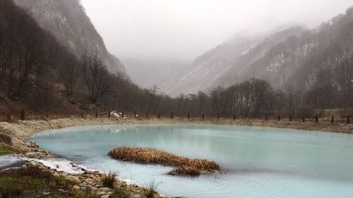 Scenic view of lake by mountains during winter