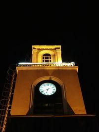 Low angle view of illuminated clock tower against sky at night