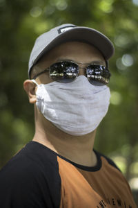 Portrait of man wearing sunglasses standing against tree