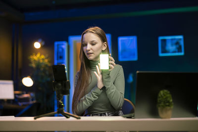 Portrait of young woman using mobile phone at restaurant