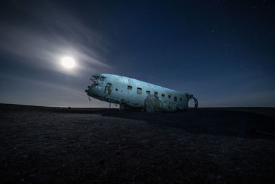 Abandoned airplane against sky at night