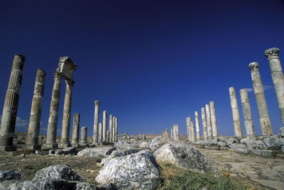 Old ruins on field against clear blue sky