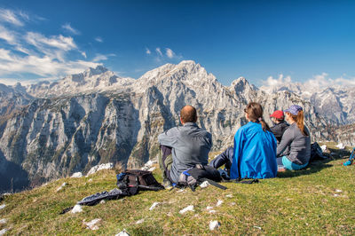 Rear view of people looking at view while sitting on mountain