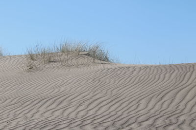 Sand dunes in desert against clear blue sky