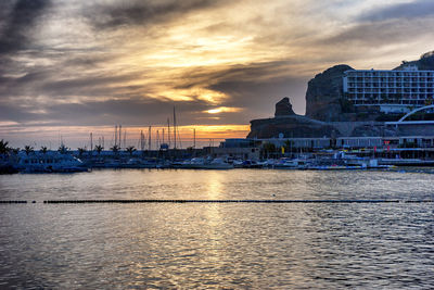 Scenic view of sea by buildings against sky during sunset