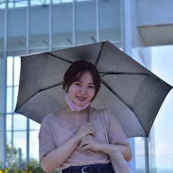 Portrait of a smiling woman standing in rain