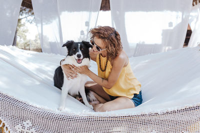 Smiling woman with dog sitting on hammock