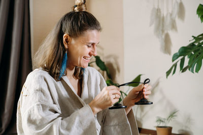 Side view of young woman applying make-up to daughter at home