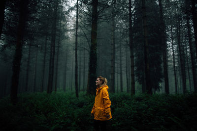 Girl standing by trees in forest