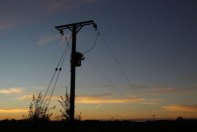 Low angle view of silhouette electricity pylon against sky during sunset