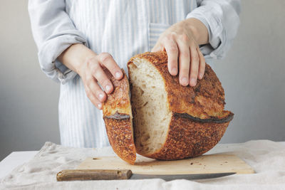 Midsection of chef cutting bread on table