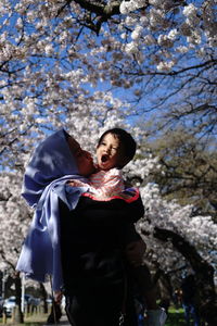 Low angle view of young woman standing against trees