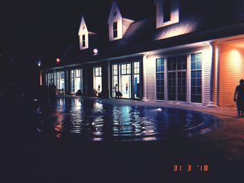 Reflection of illuminated building in swimming pool at night