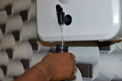 Close-up of hand holding water bottle and pour water from purifier.