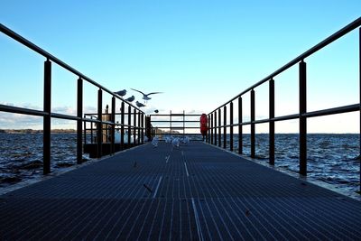 Bridge over sea against clear blue sky